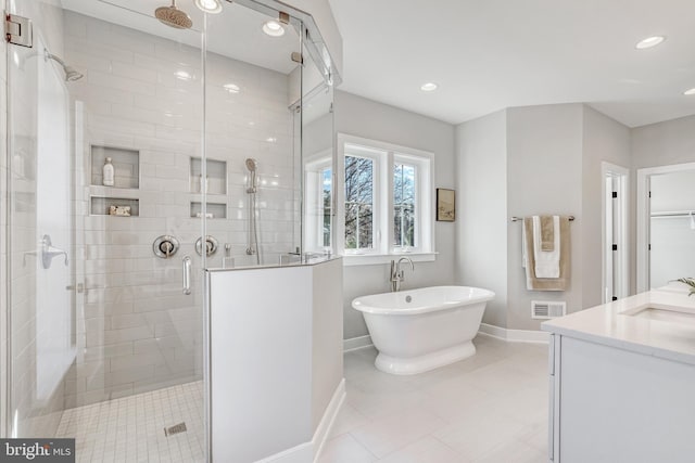 full bathroom featuring recessed lighting, visible vents, a freestanding bath, a stall shower, and baseboards