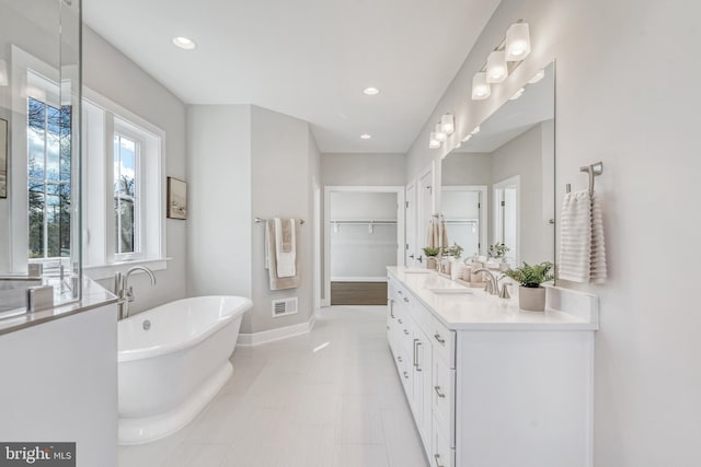 full bath featuring a walk in closet, a soaking tub, baseboards, and recessed lighting