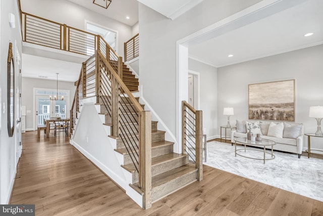 staircase with an inviting chandelier, baseboards, wood finished floors, and recessed lighting