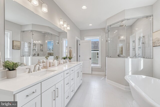 full bath featuring double vanity, baseboards, a freestanding bath, a shower stall, and a sink