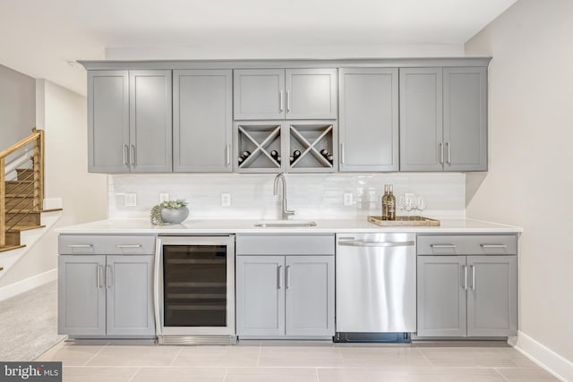 bar featuring beverage cooler, a sink, stainless steel dishwasher, stairway, and decorative backsplash