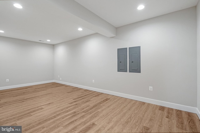 spare room featuring light wood-style floors, electric panel, and baseboards