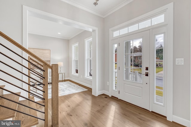 foyer featuring ornamental molding, wood-type flooring, stairway, and baseboards