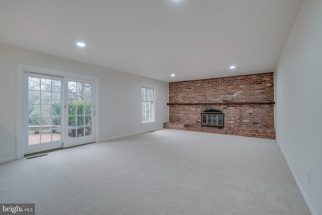 unfurnished living room with carpet floors, a brick fireplace, visible vents, and baseboards