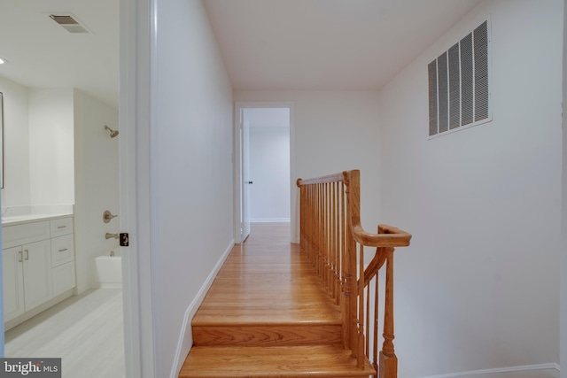 staircase with wood finished floors, visible vents, and baseboards