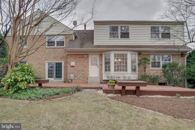 traditional home with a front lawn, brick siding, and a wooden deck