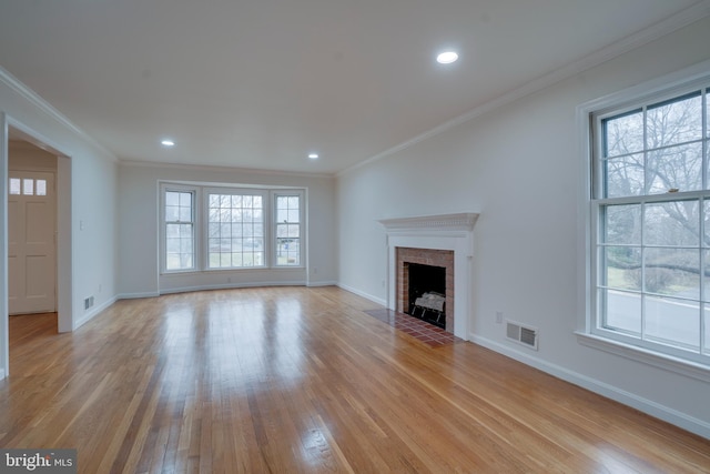 unfurnished living room featuring light wood-type flooring, a fireplace, visible vents, and crown molding