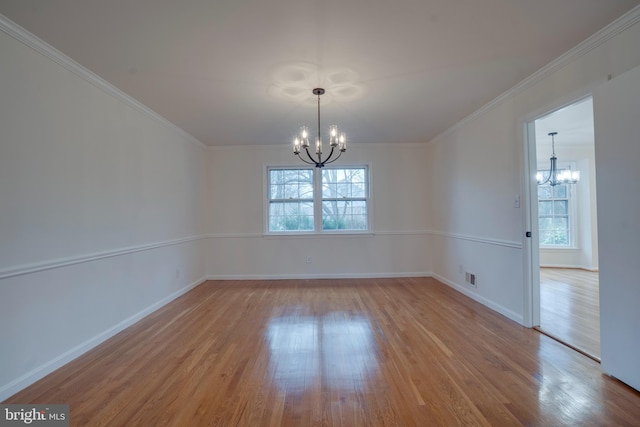 empty room featuring baseboards, visible vents, ornamental molding, wood finished floors, and a notable chandelier