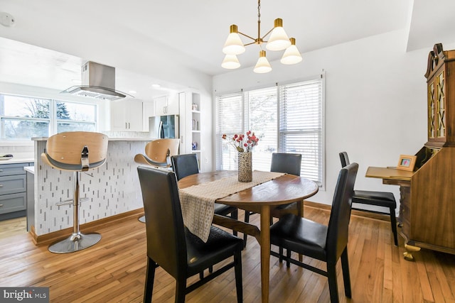 dining room with light wood-type flooring, an inviting chandelier, baseboards, and a wealth of natural light