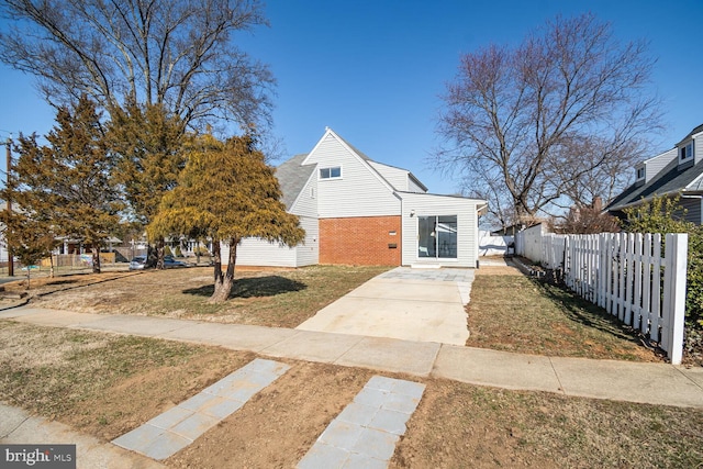 view of front facade with brick siding, fence, and a front lawn