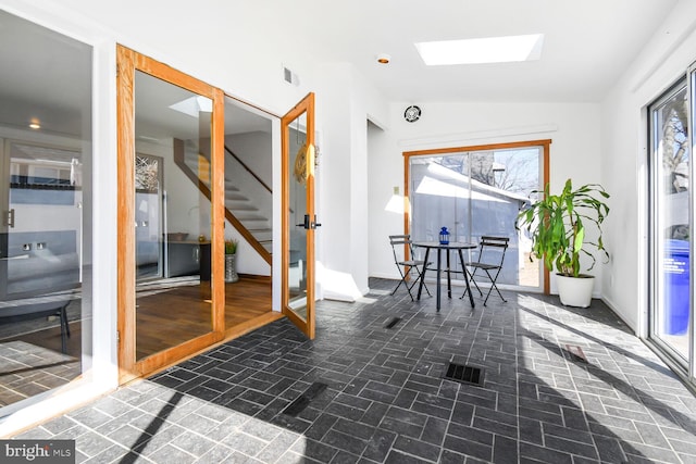 interior space featuring lofted ceiling with skylight, baseboards, stairs, and visible vents