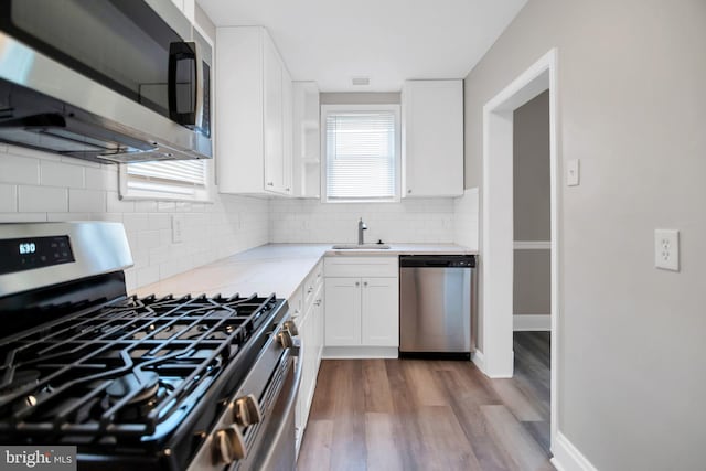 kitchen featuring wood finished floors, visible vents, a sink, white cabinetry, and appliances with stainless steel finishes