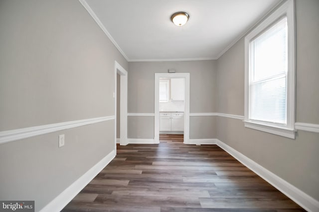 unfurnished room with ornamental molding, dark wood finished floors, and baseboards