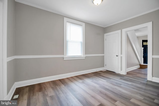 spare room with crown molding, baseboards, and wood finished floors