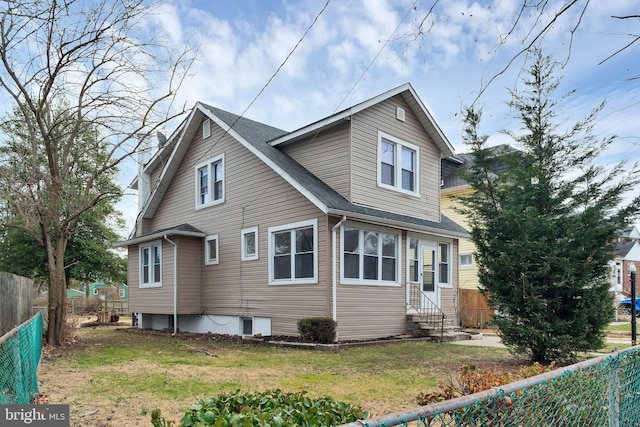 view of property exterior featuring a shingled roof, entry steps, a fenced backyard, and a yard