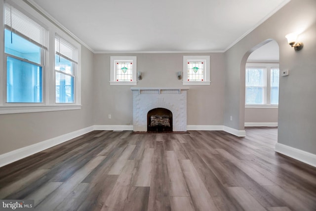 unfurnished living room with a brick fireplace, crown molding, and baseboards