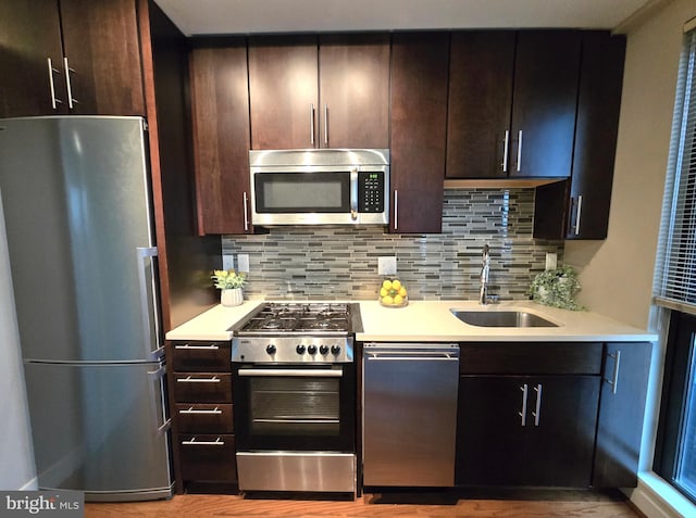 kitchen with stainless steel appliances, light countertops, a sink, and backsplash