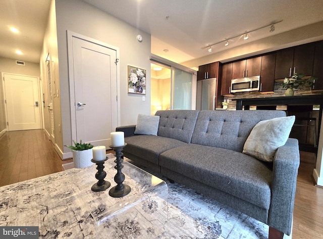 living room with wood finished floors, visible vents, and baseboards