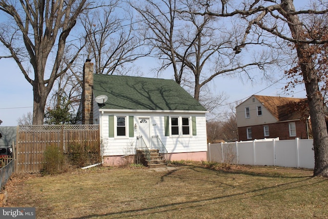 cape cod house featuring entry steps, a front lawn, a chimney, and fence private yard