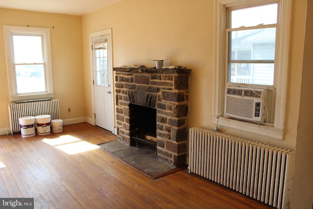 unfurnished living room featuring hardwood / wood-style floors, radiator heating unit, a fireplace, and baseboards