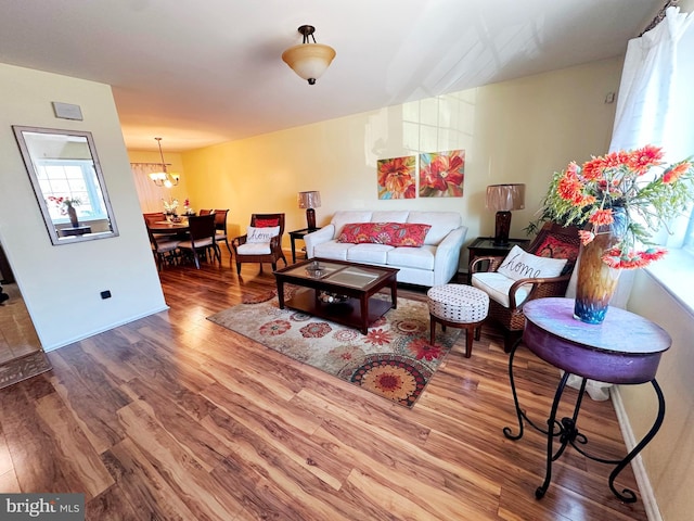 living room featuring an inviting chandelier, baseboards, and wood finished floors