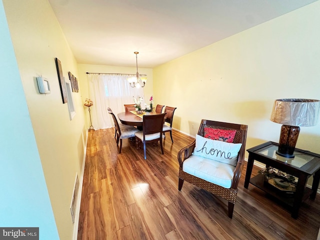 dining room with a chandelier, baseboards, and wood finished floors