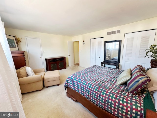 bedroom featuring carpet, visible vents, and multiple closets