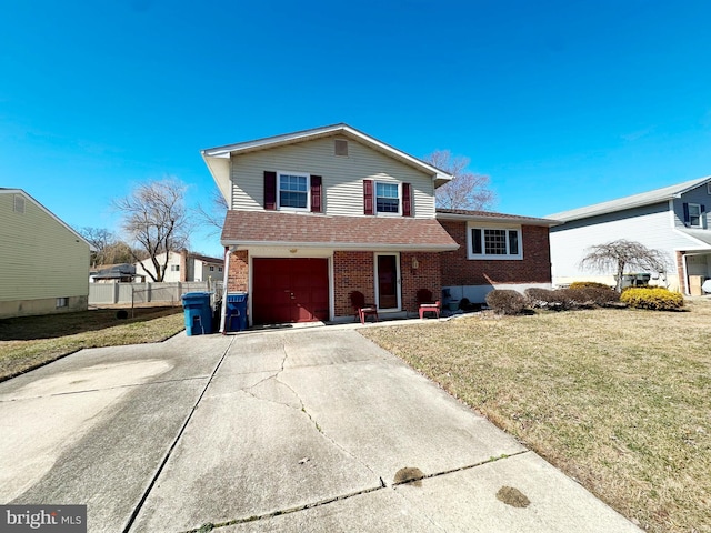 tri-level home with a front yard, concrete driveway, brick siding, and fence