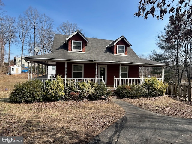 farmhouse inspired home featuring covered porch and fence