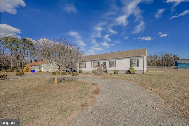 view of front facade with driveway, a front lawn, and fence