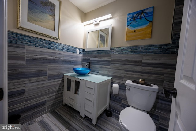 bathroom featuring toilet, tile walls, and vanity