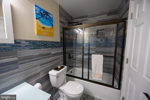 bathroom featuring shower / bath combination with glass door, tile walls, and toilet