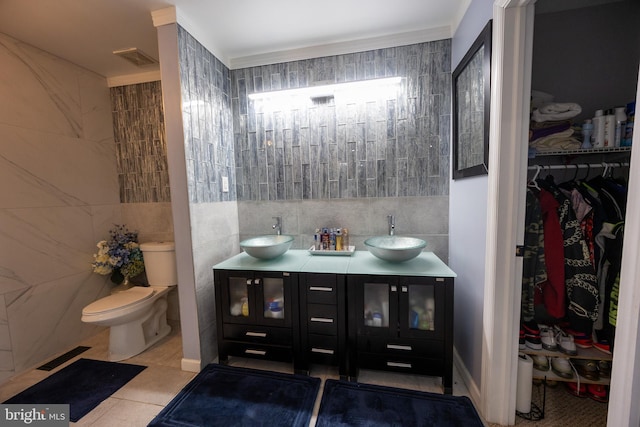 bathroom featuring toilet, a sink, and tile walls