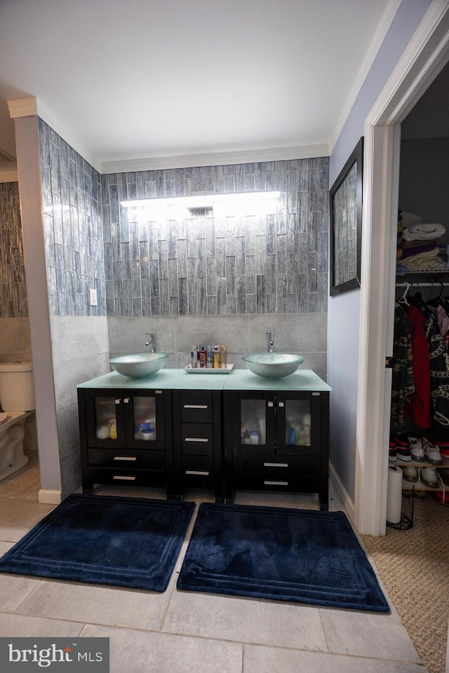 bathroom featuring double vanity, a sink, toilet, and a walk in closet