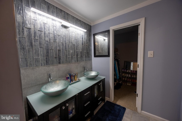 bathroom featuring crown molding, baseboards, a sink, and decorative backsplash