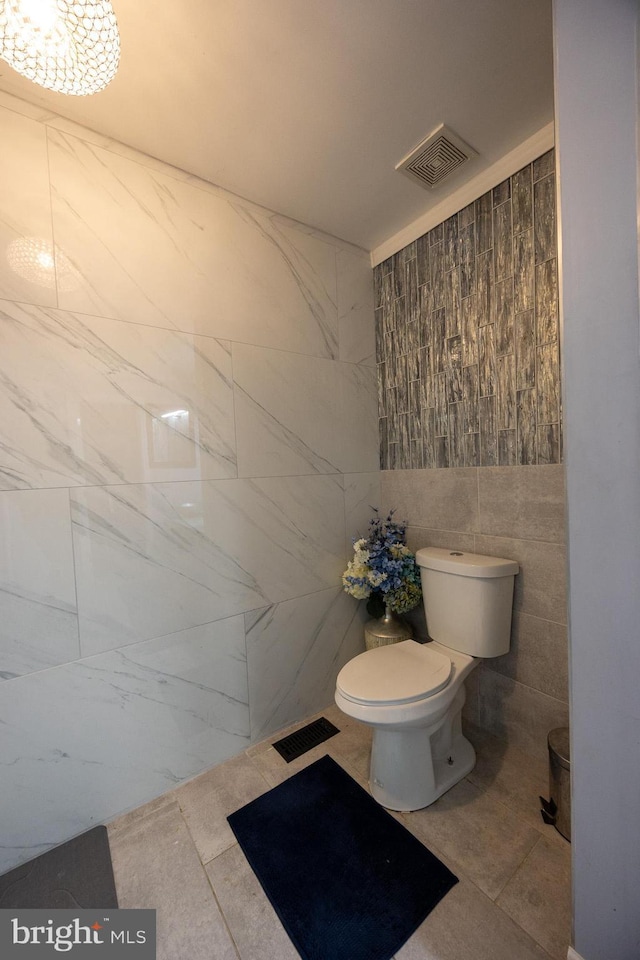 bathroom with visible vents, tile walls, and toilet