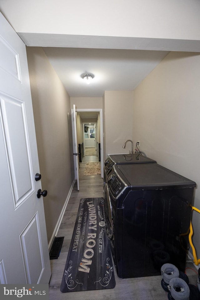 laundry room with visible vents, wood finished floors, washer and dryer, laundry area, and baseboards