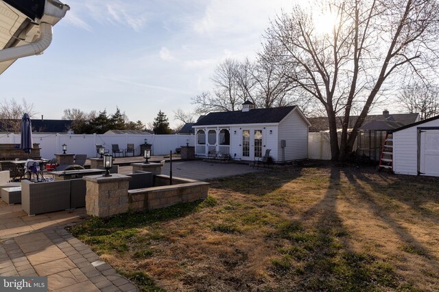 view of yard with a patio area, french doors, an outdoor structure, and a fenced backyard