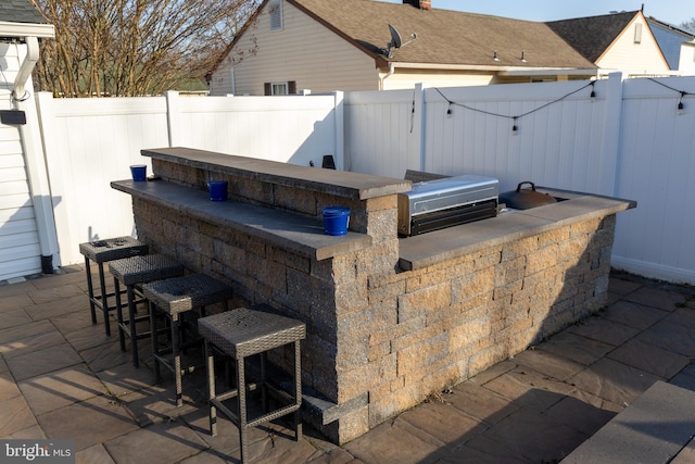 view of patio / terrace featuring a fenced backyard, outdoor dry bar, an outdoor kitchen, and area for grilling