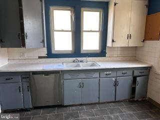 kitchen with gray cabinetry, light countertops, a sink, and stainless steel dishwasher