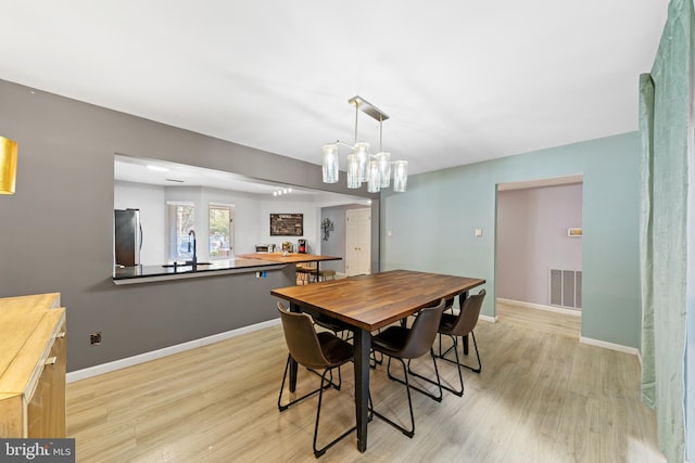 dining space with visible vents, baseboards, and light wood finished floors