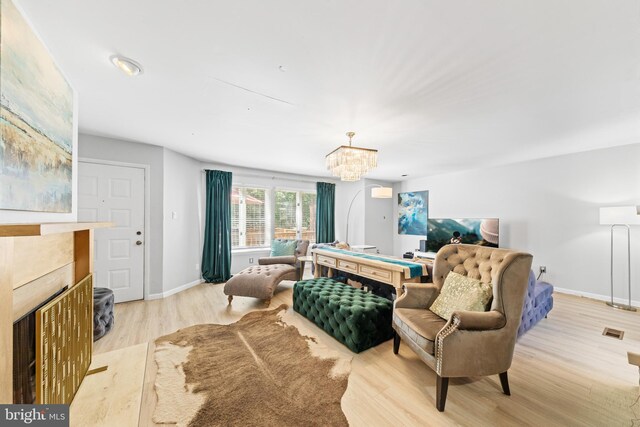 bedroom with a chandelier, light wood-style flooring, a tile fireplace, and baseboards