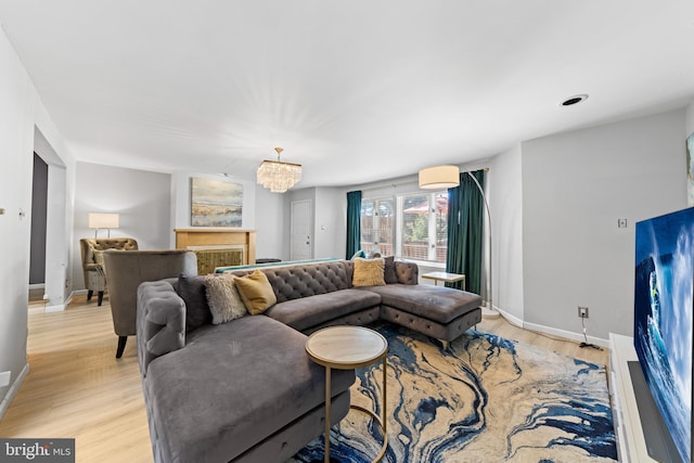 living room with a chandelier, baseboards, and light wood-style floors