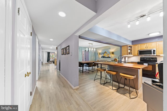 kitchen featuring light brown cabinets, a breakfast bar, black electric range, wood counters, and stainless steel microwave