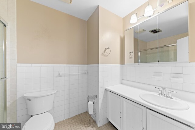 bathroom featuring toilet, tile walls, and a shower with shower door