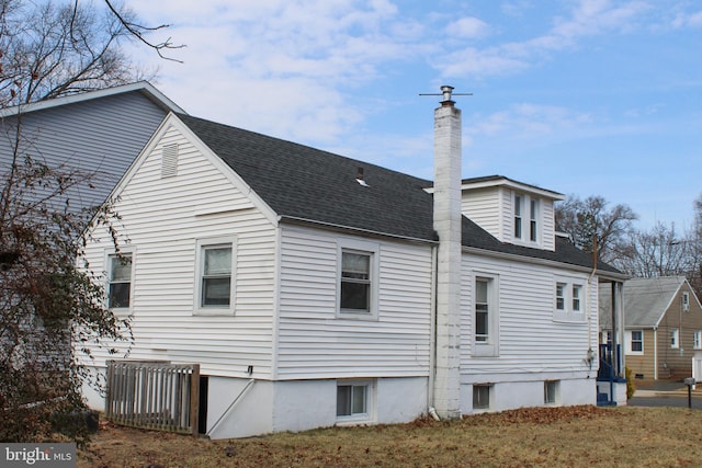 rear view of house with a shingled roof and a chimney