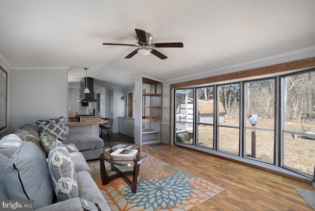 living room featuring lofted ceiling, ceiling fan, wood finished floors, and crown molding