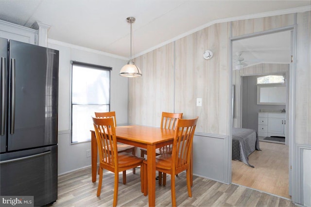 dining room with lofted ceiling, light wood-style flooring, and crown molding