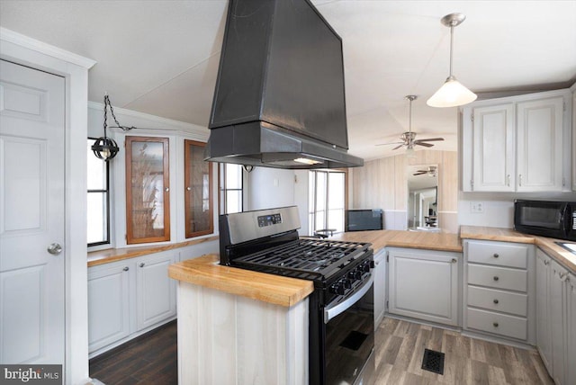 kitchen featuring black microwave, exhaust hood, wood finished floors, visible vents, and stainless steel range with gas cooktop