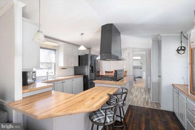 kitchen featuring dark wood-style floors, stainless steel microwave, extractor fan, a kitchen breakfast bar, and black fridge